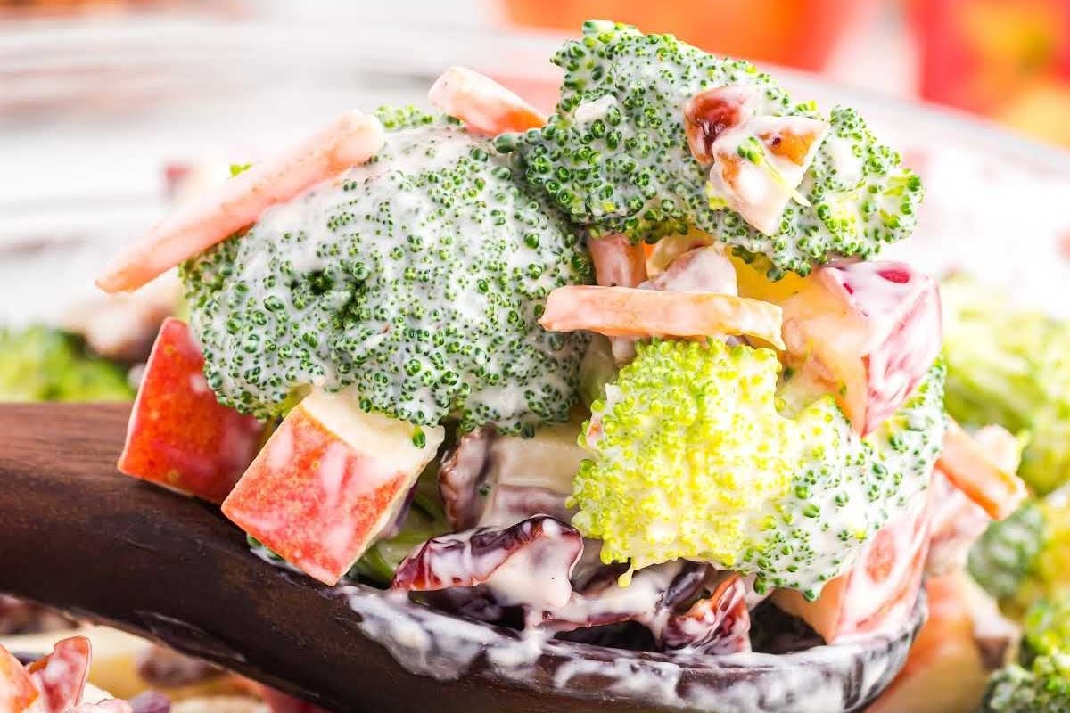 A close-up of a broccoli salad with creamy dressing and added ingredients such as apple chunks and seeds, perfect for Easter sides.