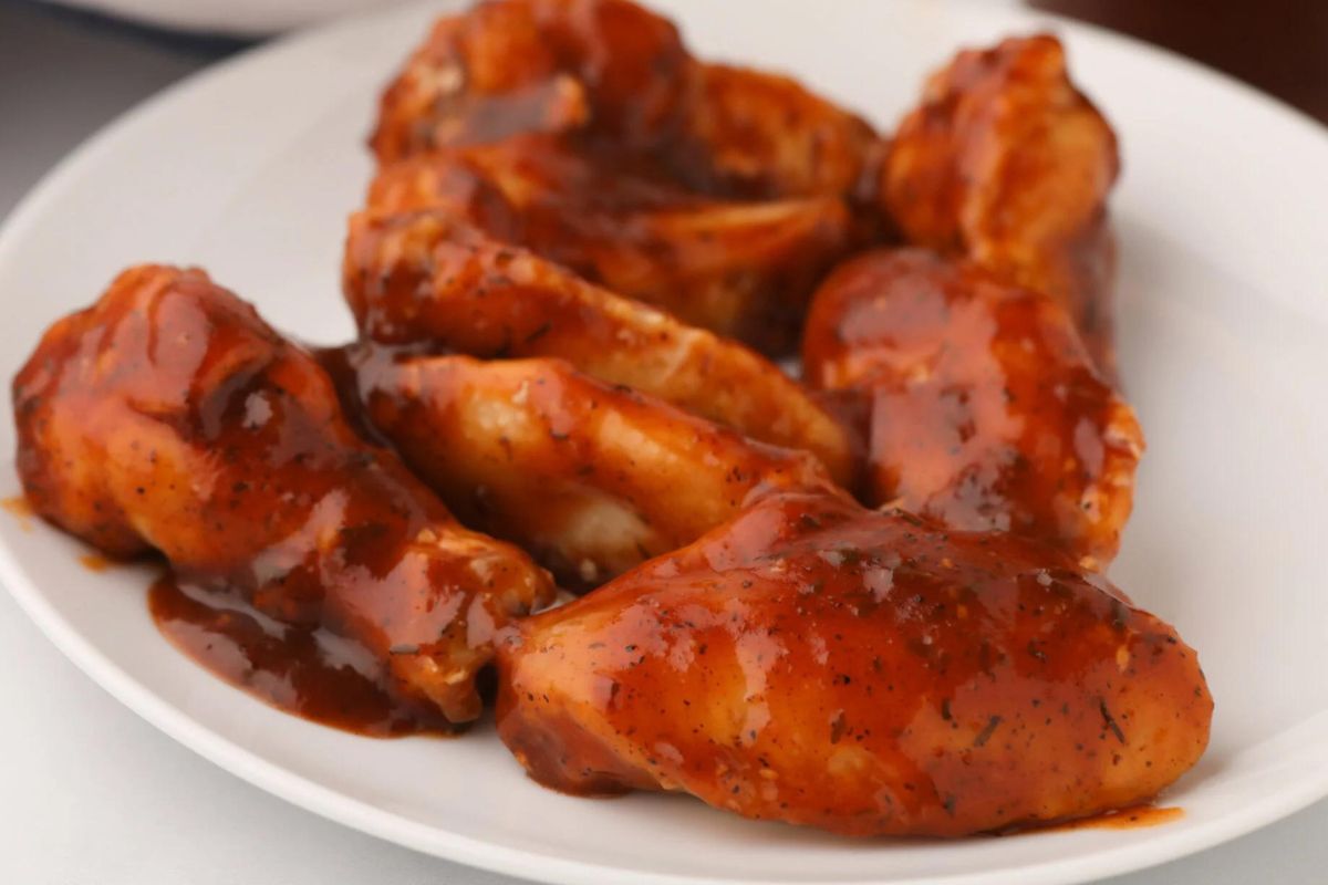 A plate of chicken wings coated in barbecue sauce.