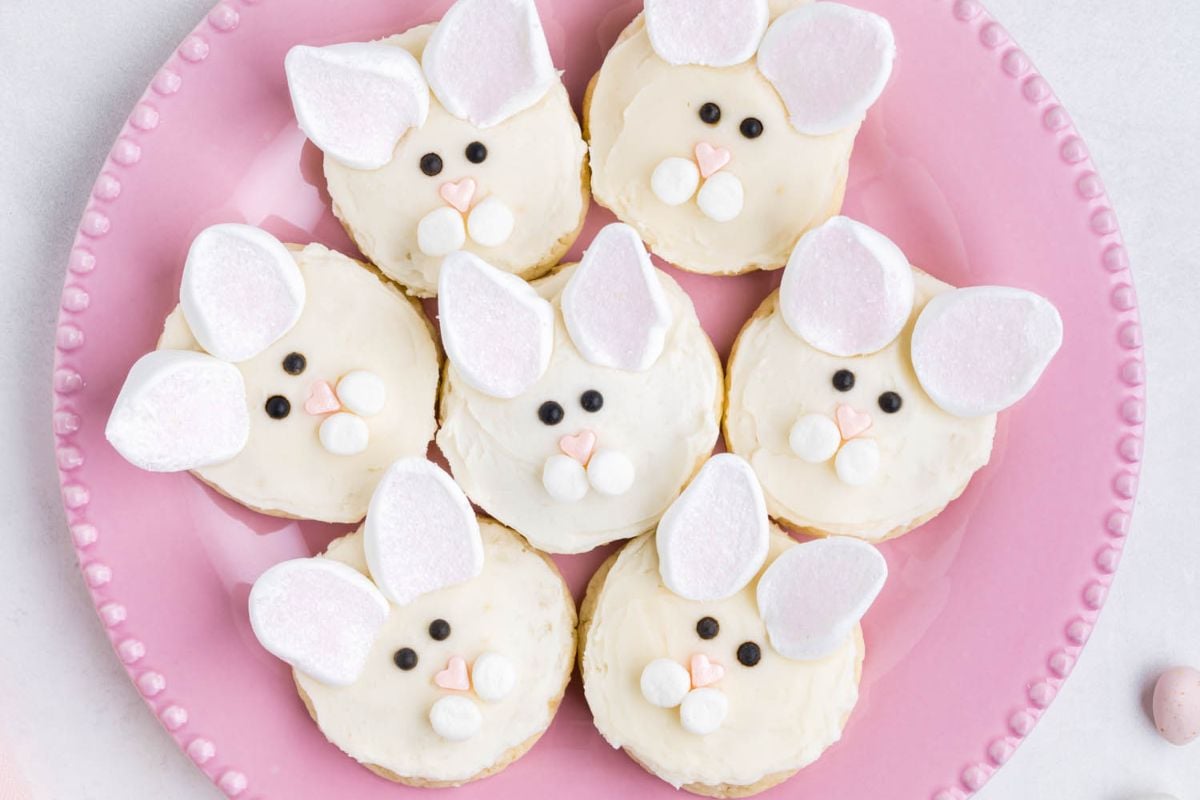A plate of Easter bunny-shaped cookies decorated with frosting and candy to resemble rabbit faces.