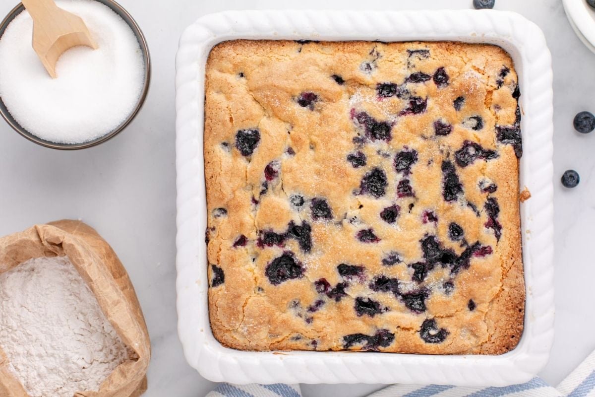 Freshly baked blueberry cake in a white dish, perfect for Father's Day breakfast, with ingredients on the side.