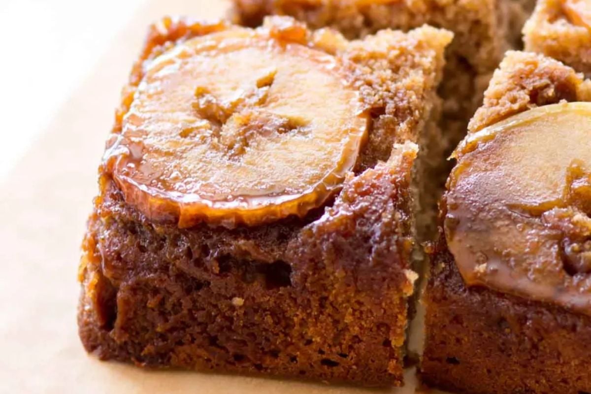Close-up of a slice of apple cake with a caramelized apple slice on top, reminiscent of classic upside down cakes.