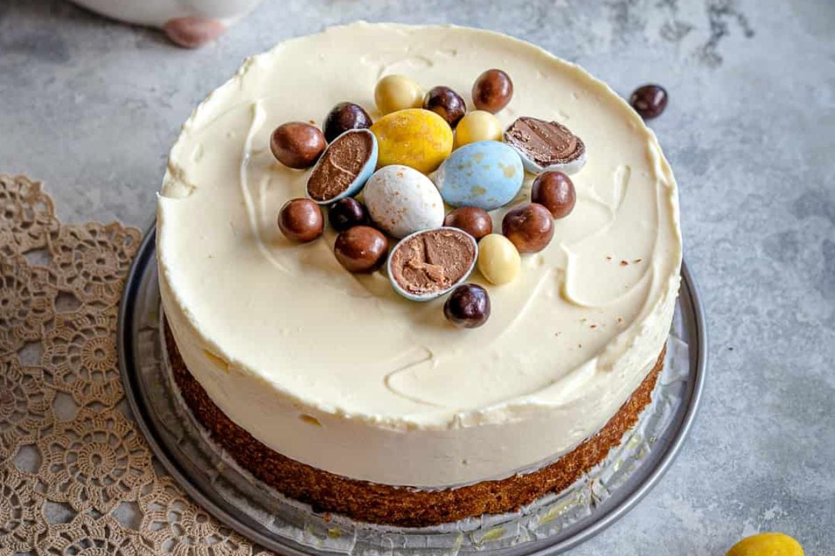 An Easter carrot cake with cream cheese frosting, decorated with chocolate Easter eggs on top.