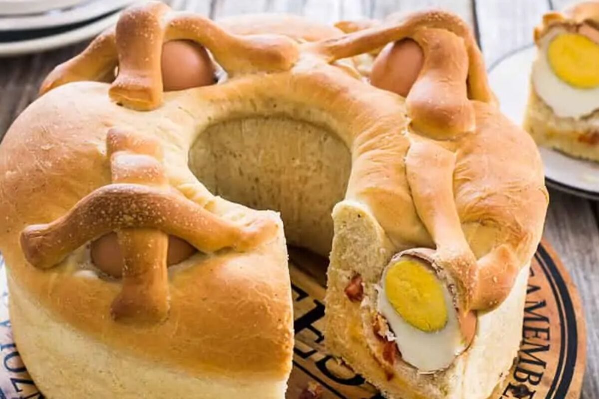 A traditional casatiello, an Italian Easter dinner bread with embedded whole eggs and slices showcasing its savory filling.