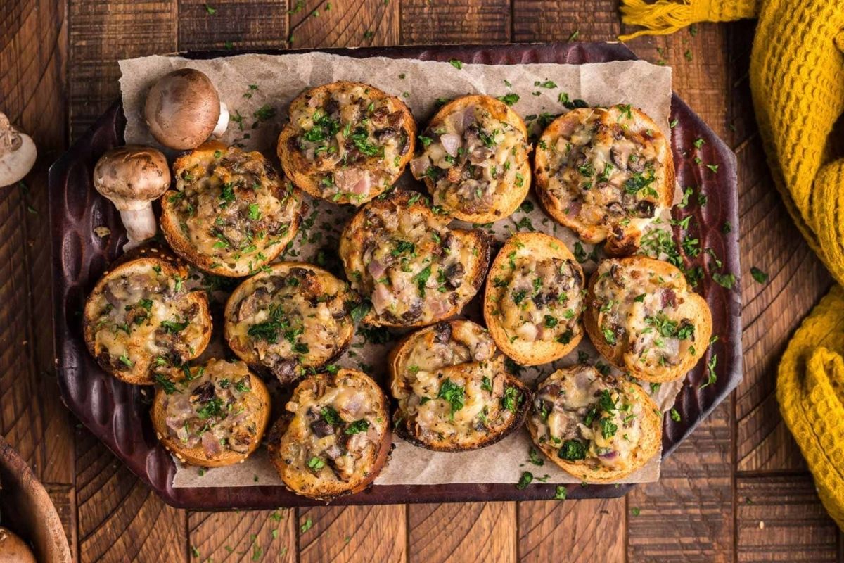 A platter of baked stuffed mushrooms garnished with herbs, part of our cheesy recipes collection.