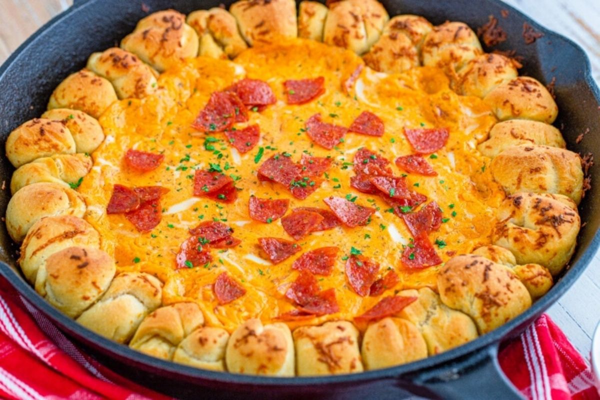 Cheesy pepperoni pizza dip with pull-apart breadsticks served in a cast-iron skillet.