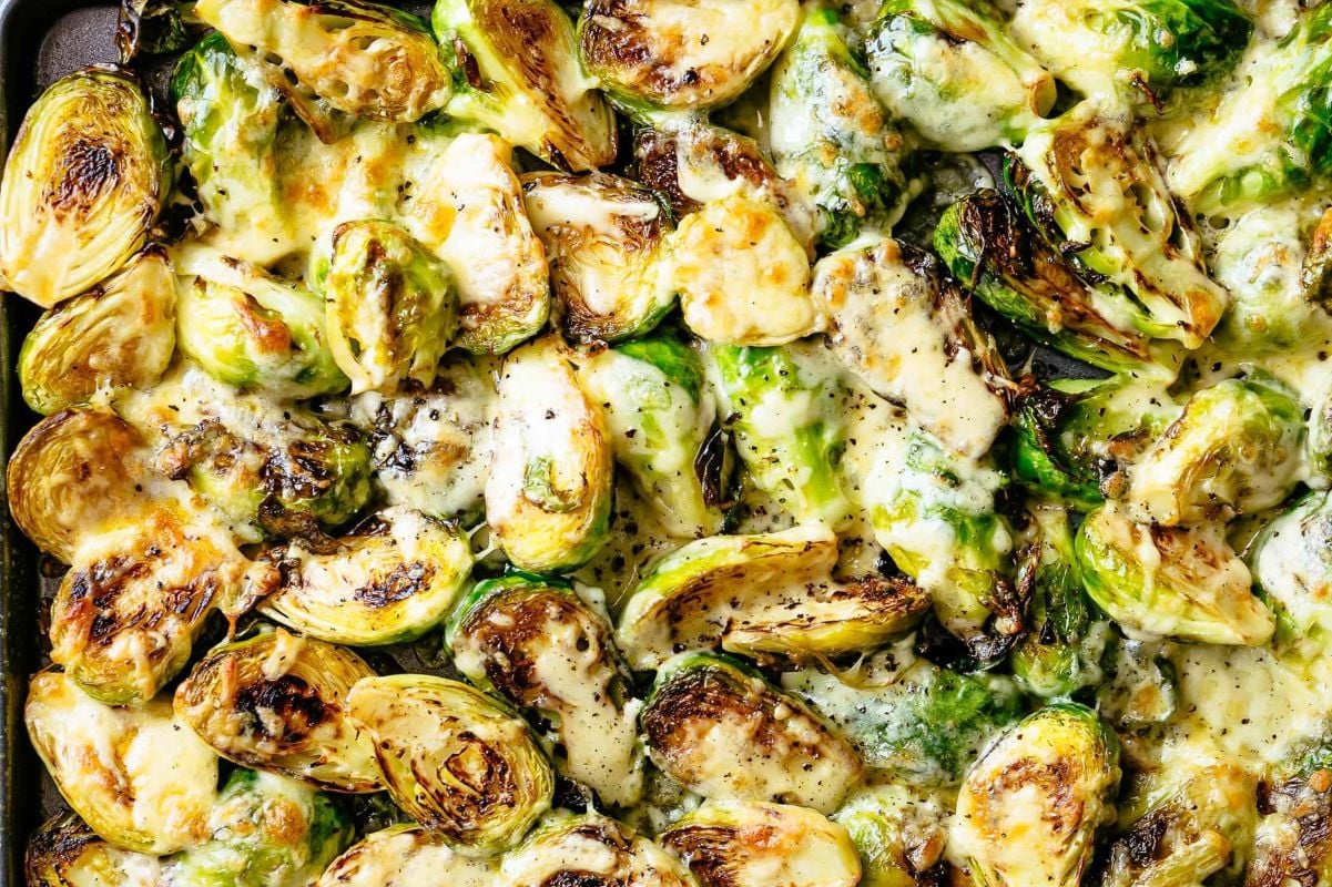 Roasted brussels sprouts with melted cheese and herbs, displayed in a close-up view of cheesy recipes.
