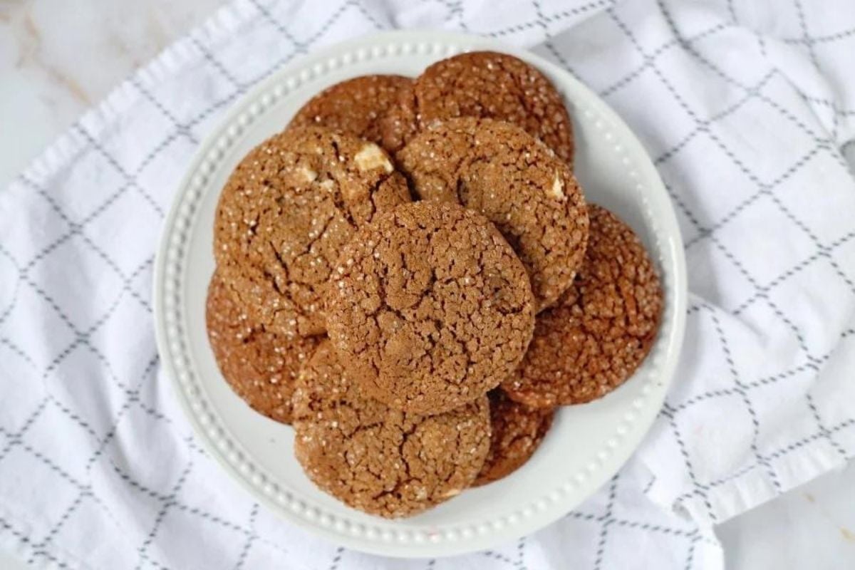 A plate of homemade ginger snap cookies from our cookie recipes on a white cloth.
