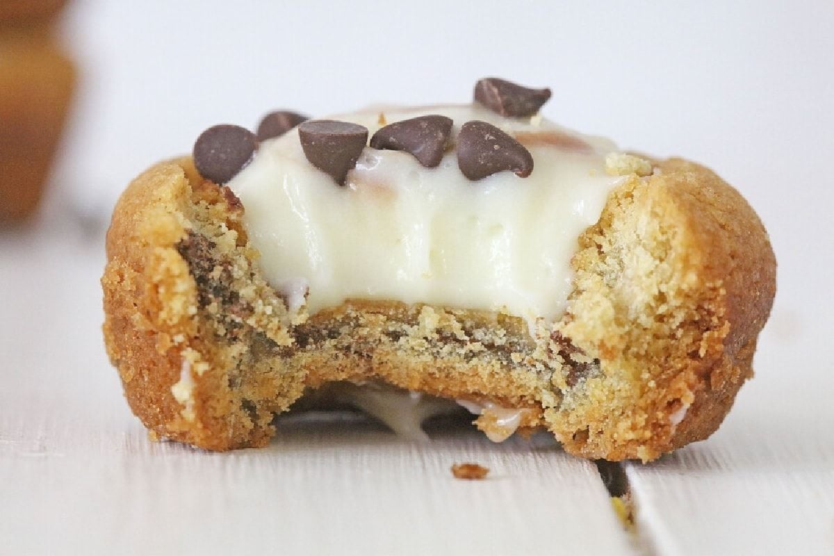 Close-up of a cookie from one of our cookie recipes with white icing and chocolate chips, showing a bite taken out.