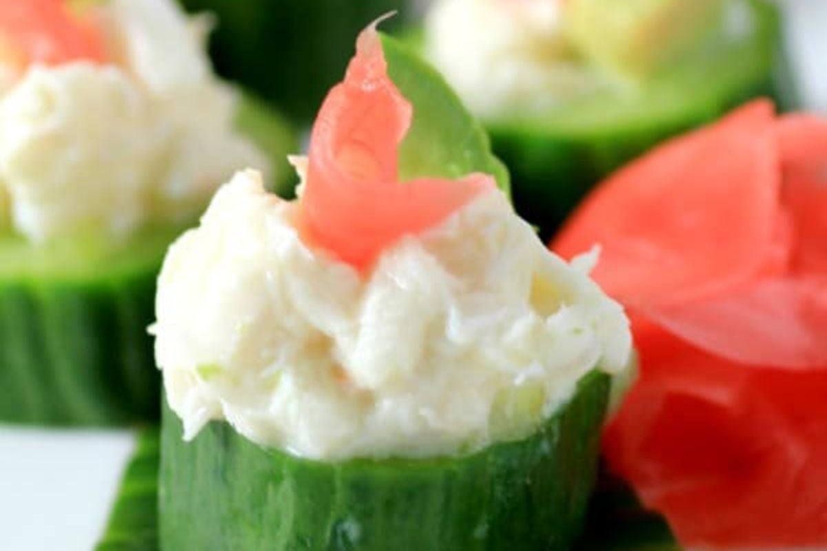 Sliced cucumber cups filled with cream cheese garnished with pink accents, perfect as an Easter appetizer.