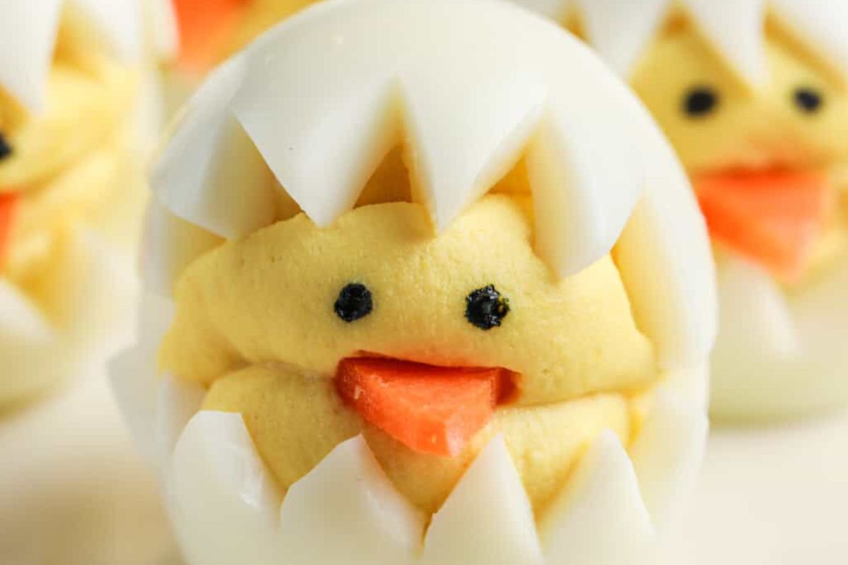 A close-up of a deviled egg creatively decorated to resemble a chick hatching from an egg, perfect as an Easter appetizer.