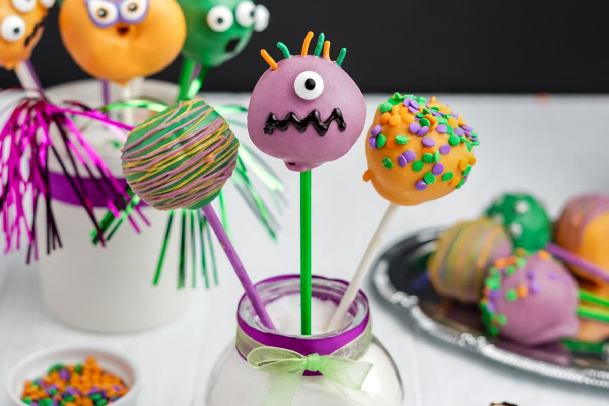 Assorted colorful handheld desserts with playful monster designs displayed on a festive table.