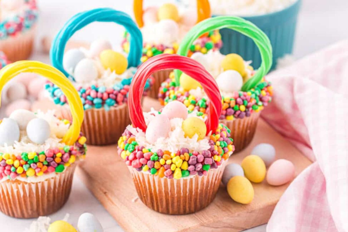 Colorful Easter desserts themed as cupcakes decorated with sprinkles, candy eggs, and fondant handles to resemble easter baskets.