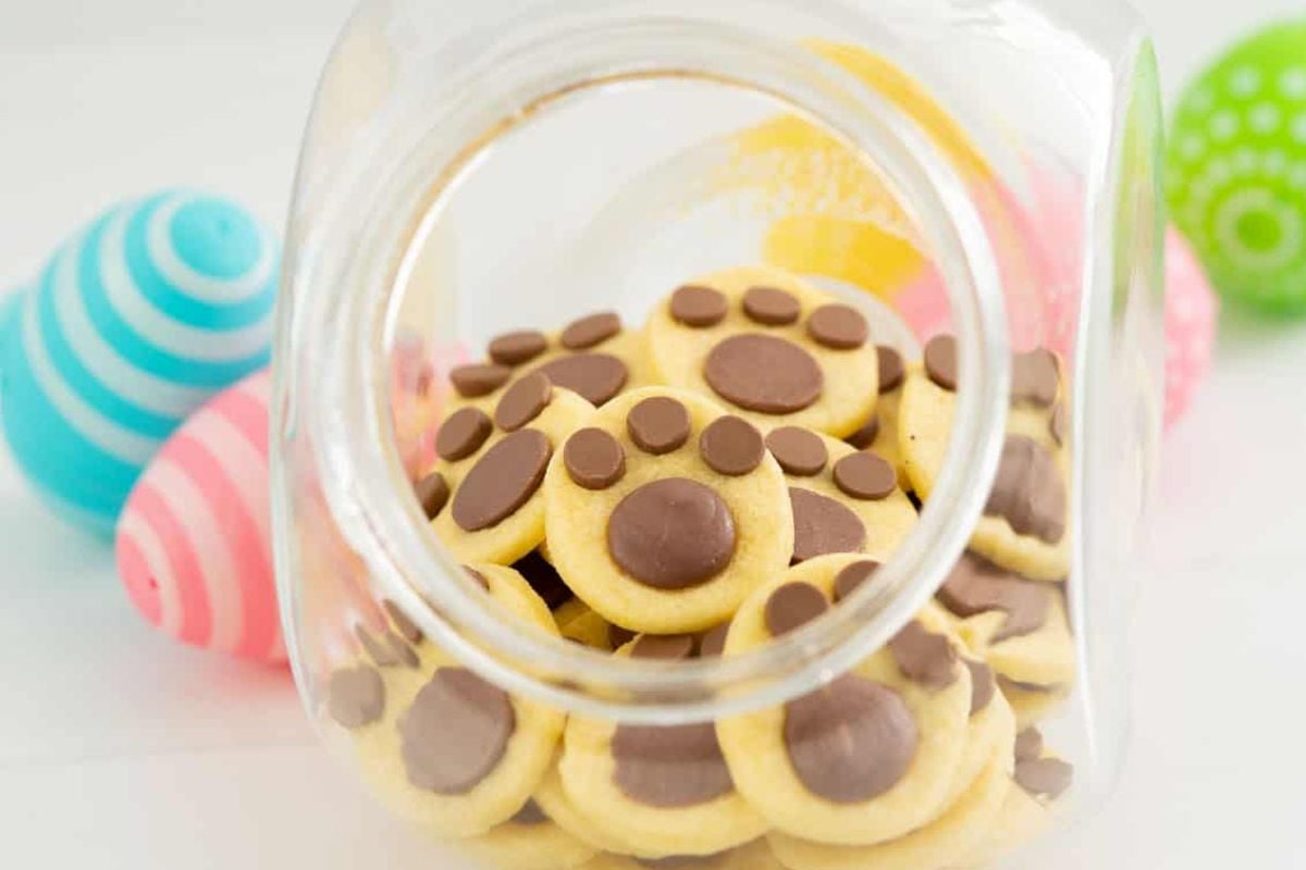 A glass jar tipped on its side spilling out Easter cookies with chocolate chips.