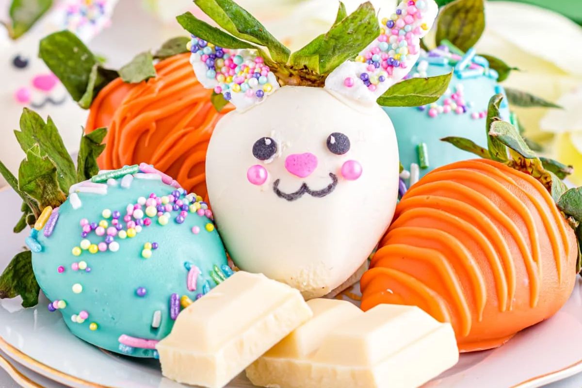 Decorative chocolate-covered strawberries with a cute face and colorful sprinkles, perfect as Easter desserts.