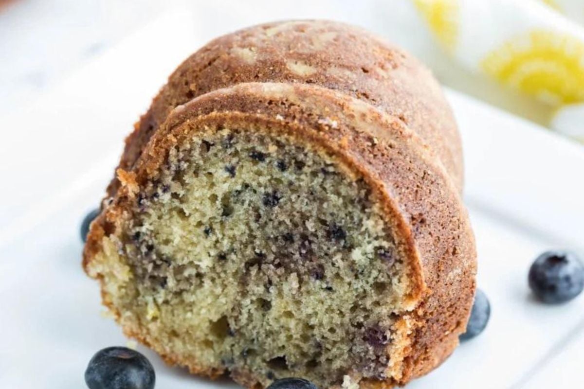 A sliced lemon blueberry Bundt cake on a white plate.