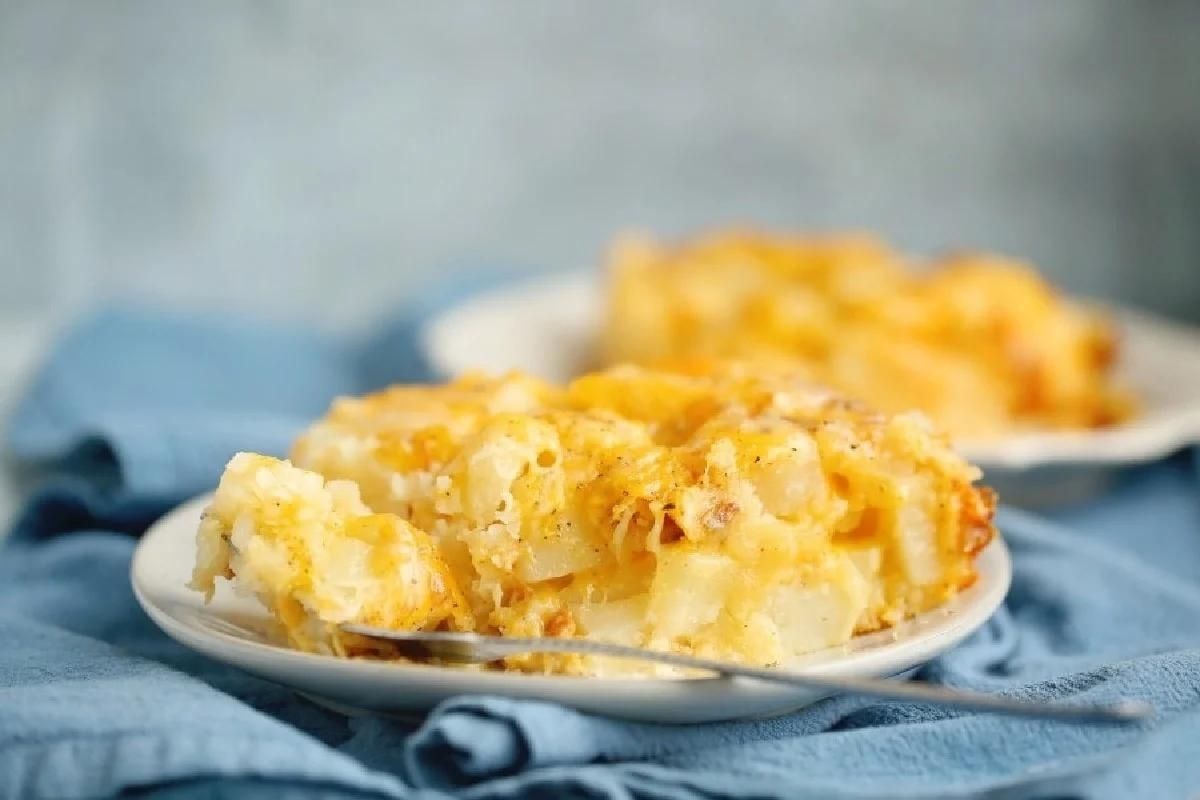 A serving of cheesy baked macaroni and cheese on a small plate with a blue napkin in the background.