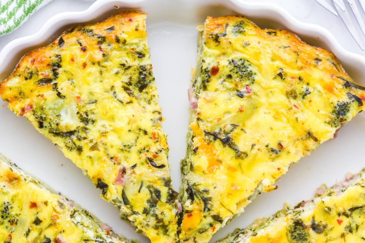 Egg, ham, and broccoli quiche on a white plate.