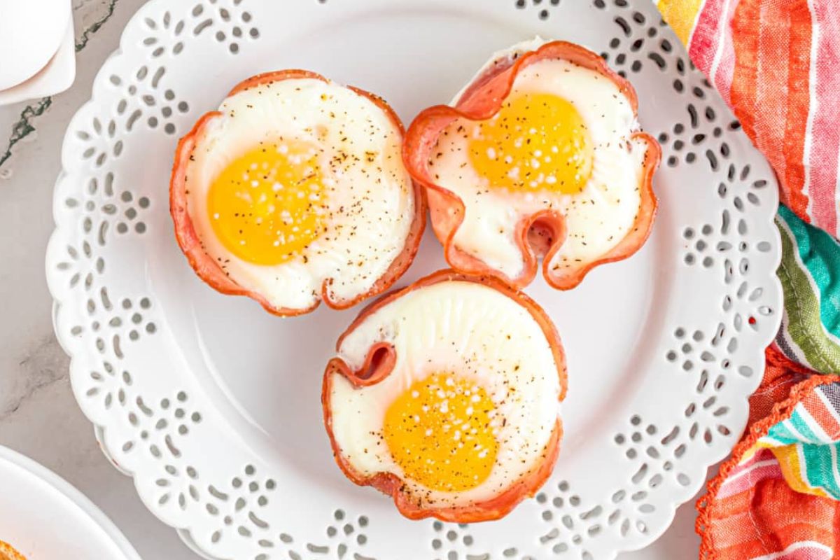 Three fried egg recipes on a plate next to a cup of coffee.