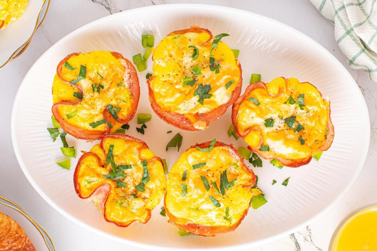 A plate full of egg recipes on a plate next to orange juice.