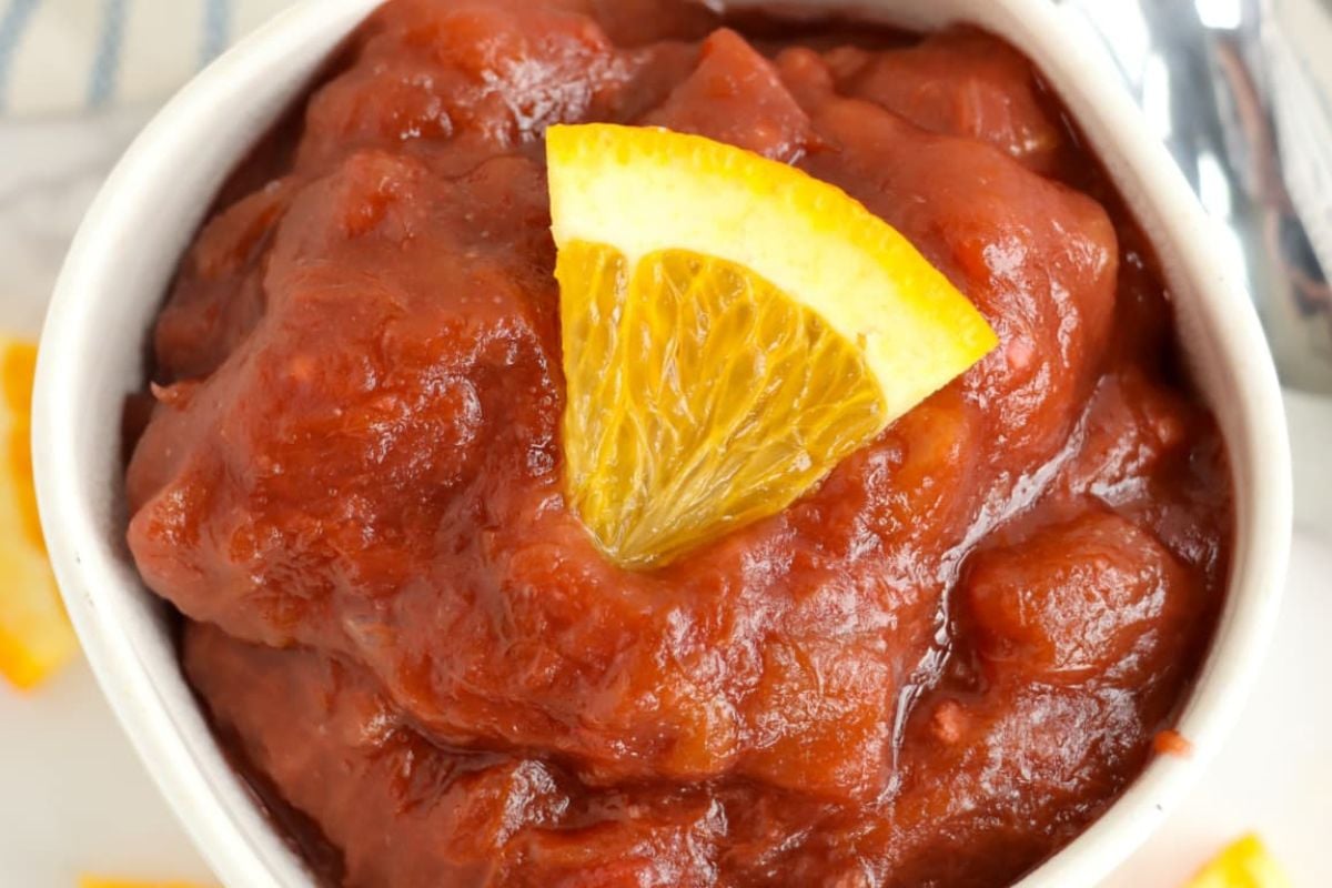 A bowl of chunky tomato and rhubarb sauce garnished with a lemon wedge.