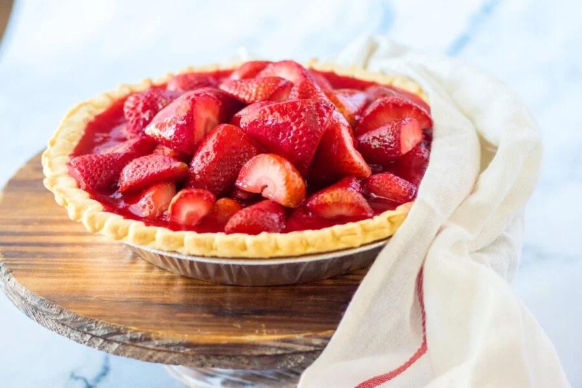 A fresh strawberry Jello pie on a wooden stand with a light-colored cloth napkin.