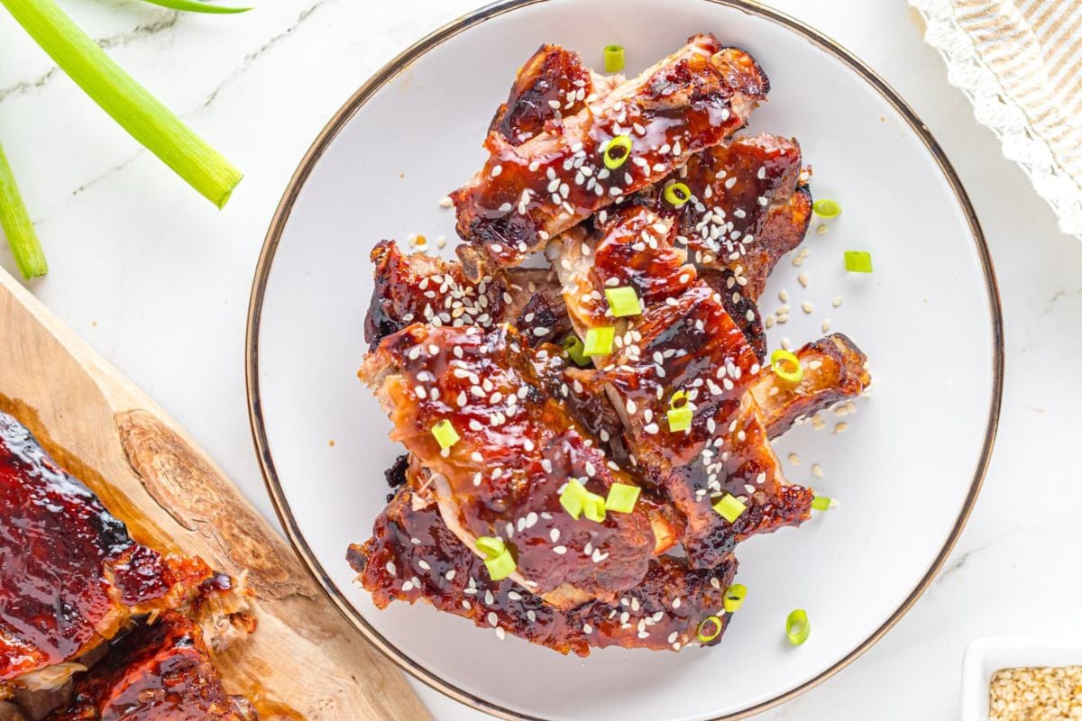 Glazed barbecue chicken wings garnished with sesame seeds and green onions on a white plate, inspired by easy rib recipes.