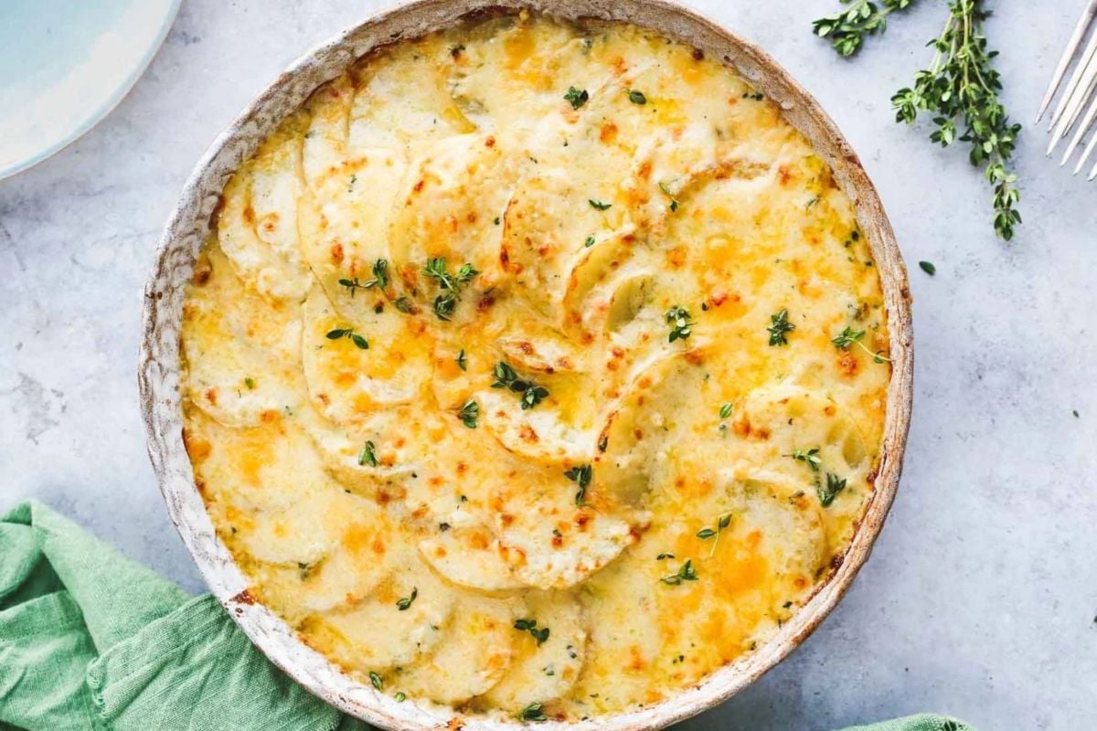A freshly baked scalloped potatoes dish garnished with herbs, perfect for Easter dinner.