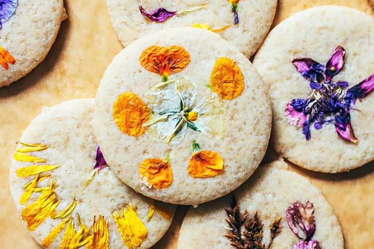 Decorative Easter cookies adorned with edible flowers on a parchment surface.