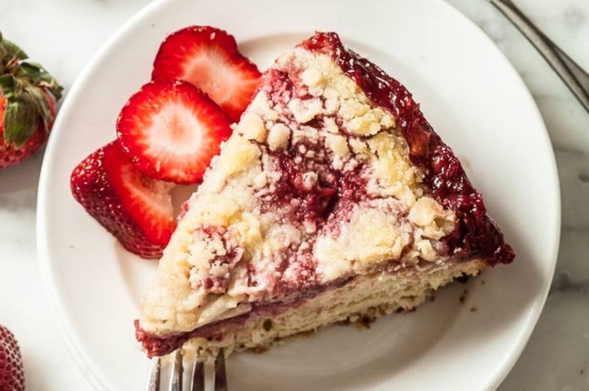 A slice of strawberry crumble Easter cake served with fresh strawberries on the side.