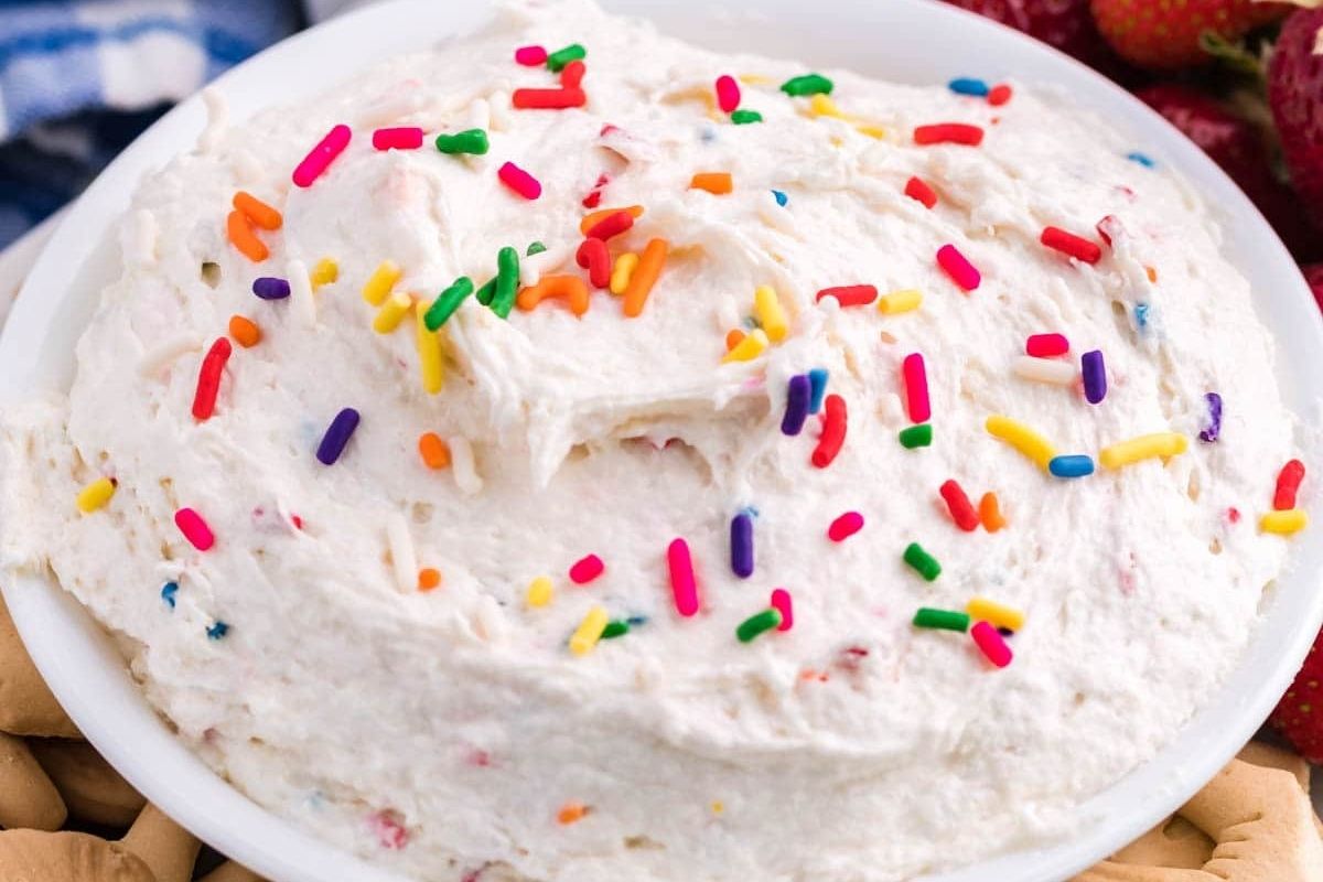 A bowl of creamy whipped cream topped with colorful sprinkles.
