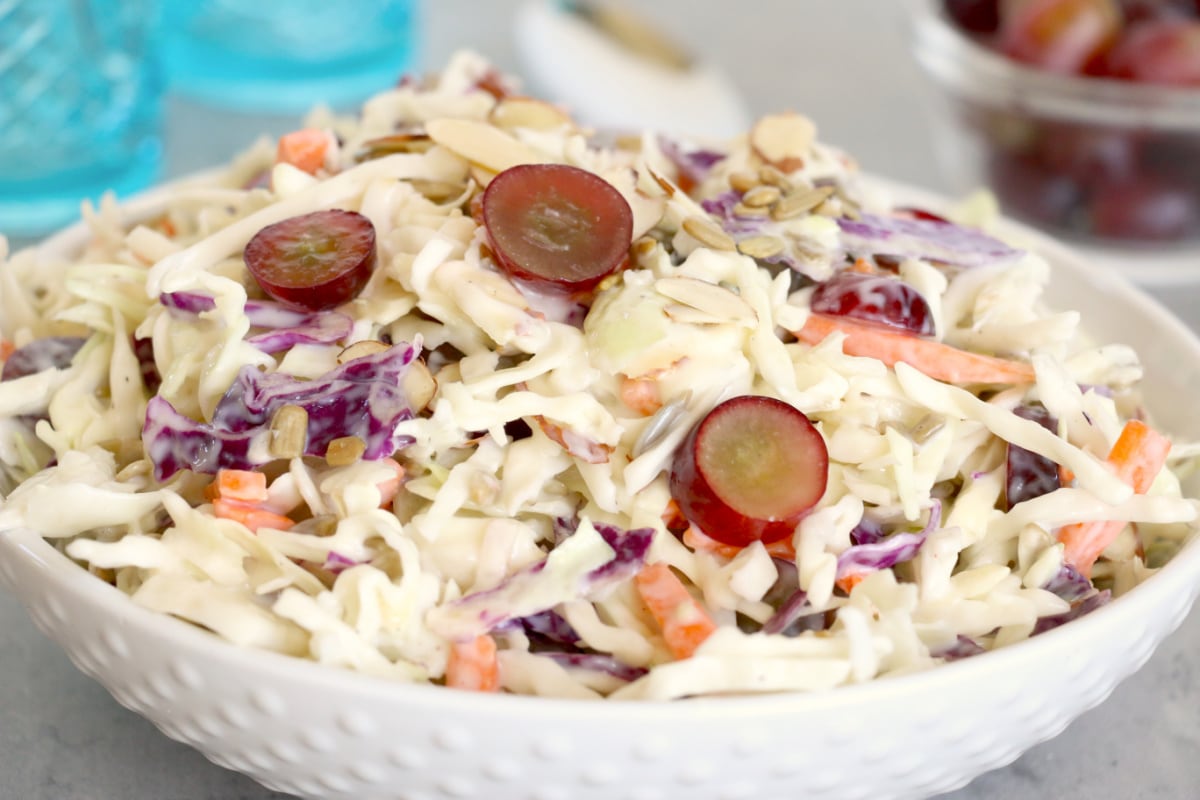 A bowl of grandma's recipes coleslaw with sliced grapes and almonds.