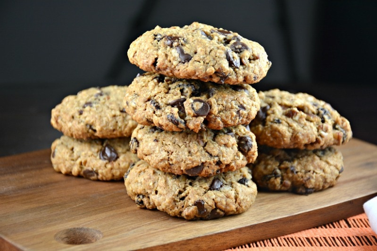 A stack of chocolate chip oatmeal cookies from grandma's recipes on a wooden cutting board.