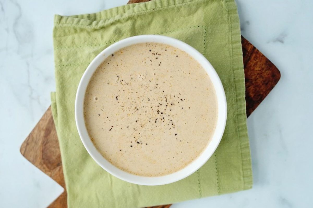 A bowl of soup recipes sitting on a cutting board.