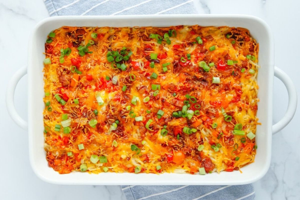 A casserole dish filled with bacon, tomatoes, onions, and egg recipes.