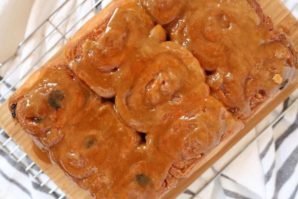 A tray of sticky cinnamon rolls with a caramel glaze and nuts, viewed from above.