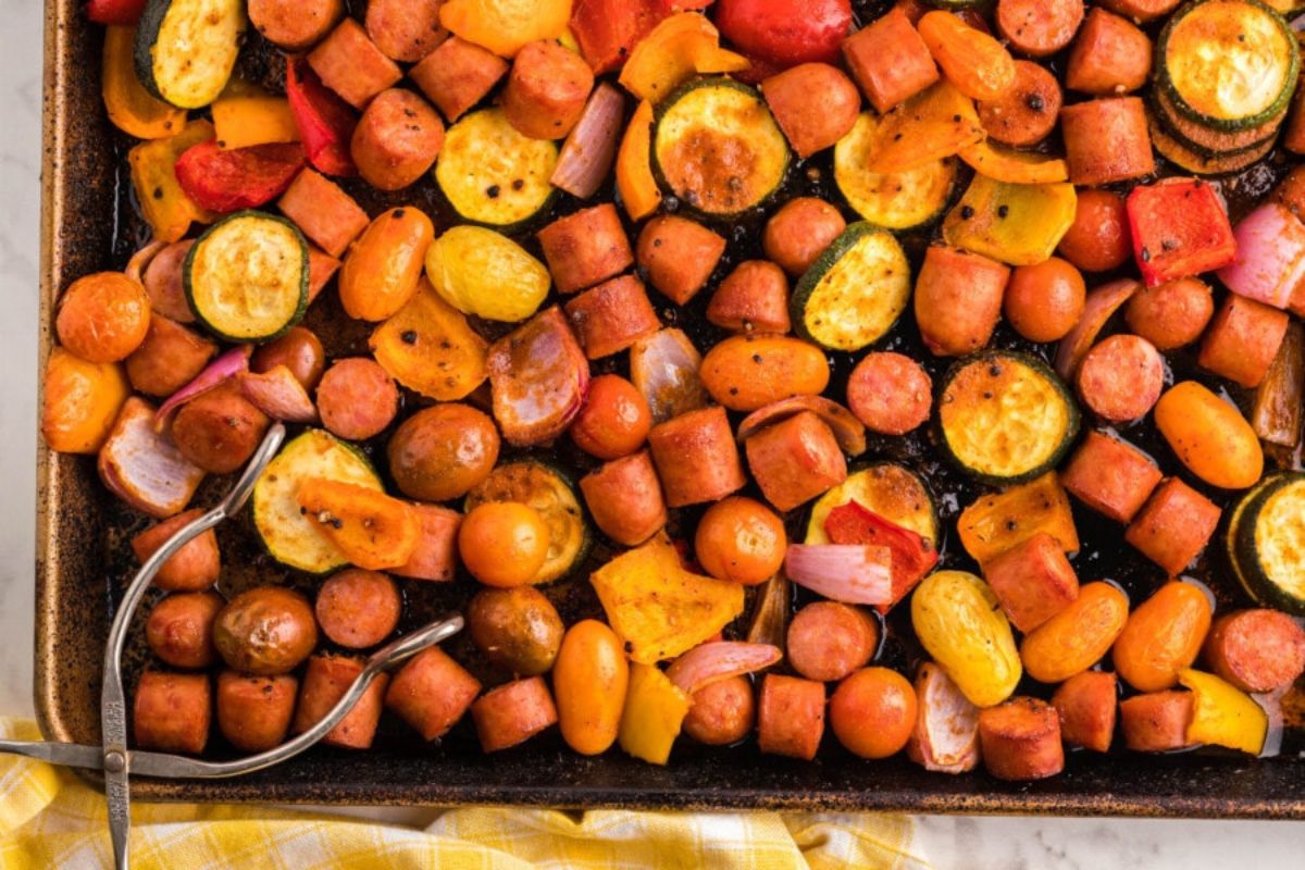 A baking sheet full of grilled vegetables and sausages for dinner recipes.