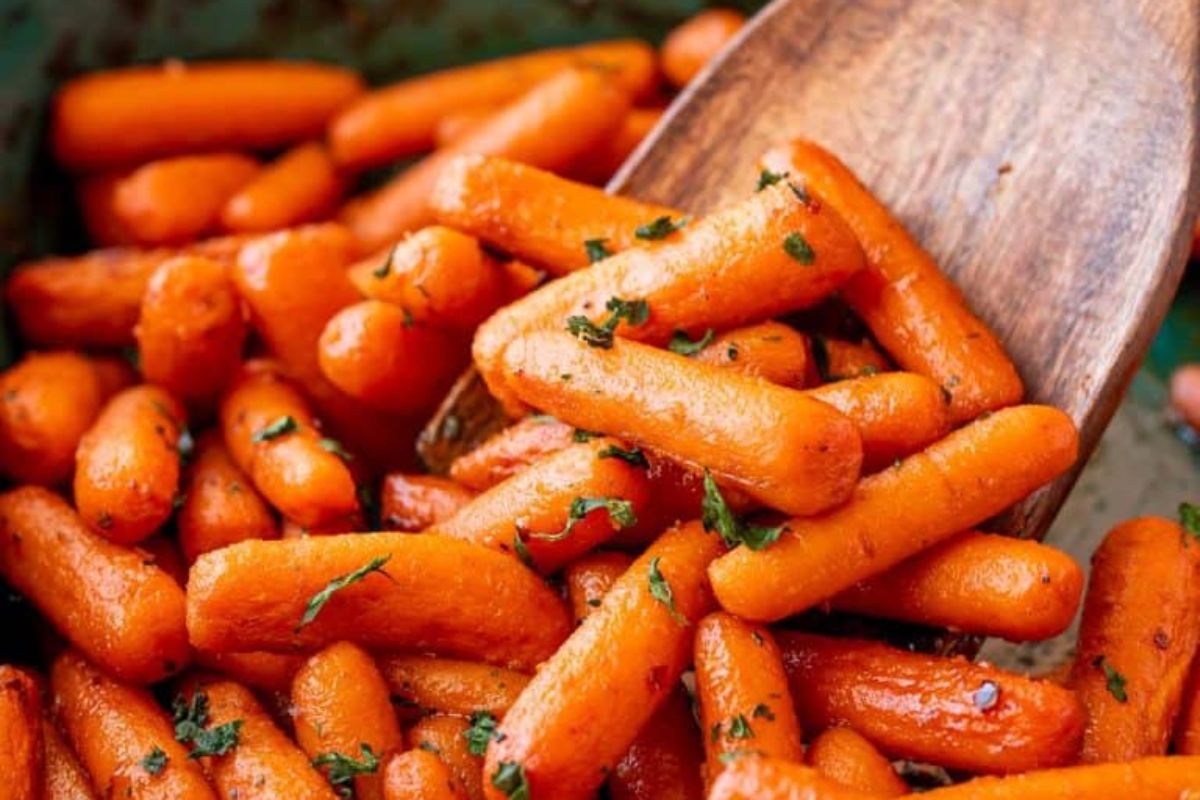 Glazed carrots seasoned with herbs, perfect for Easter sides, on a wooden spatula.