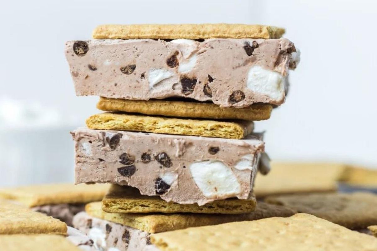 A stack of creamy dessert bars with a layer of chocolate chip and marshmallow filling between two graham cracker pieces.