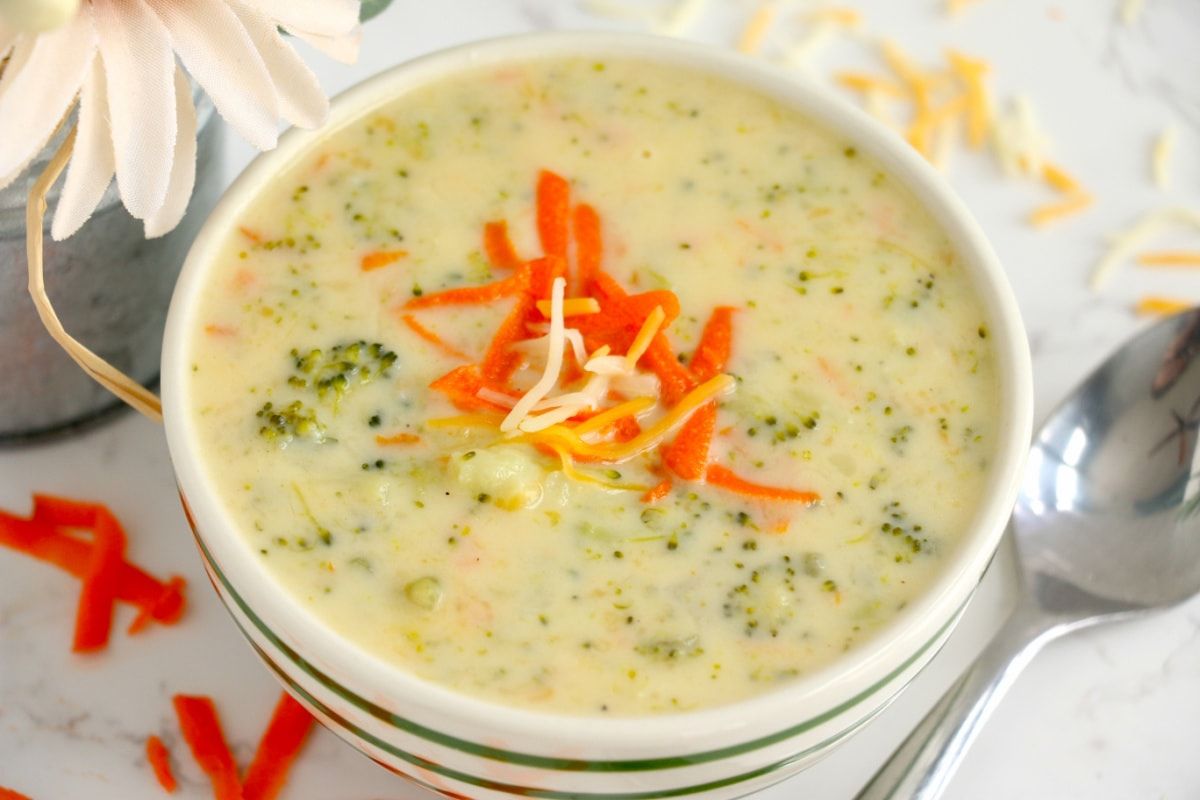 A bowl of broccoli soup recipes with carrots and cheese.
