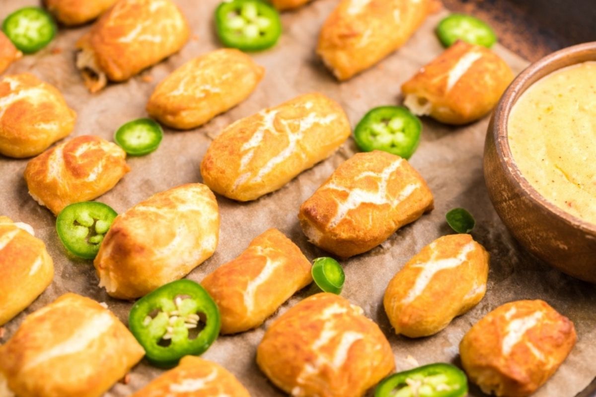 Golden pastries served with a cheesy dipping sauce, garnished with sliced jalape&ntilde;os.