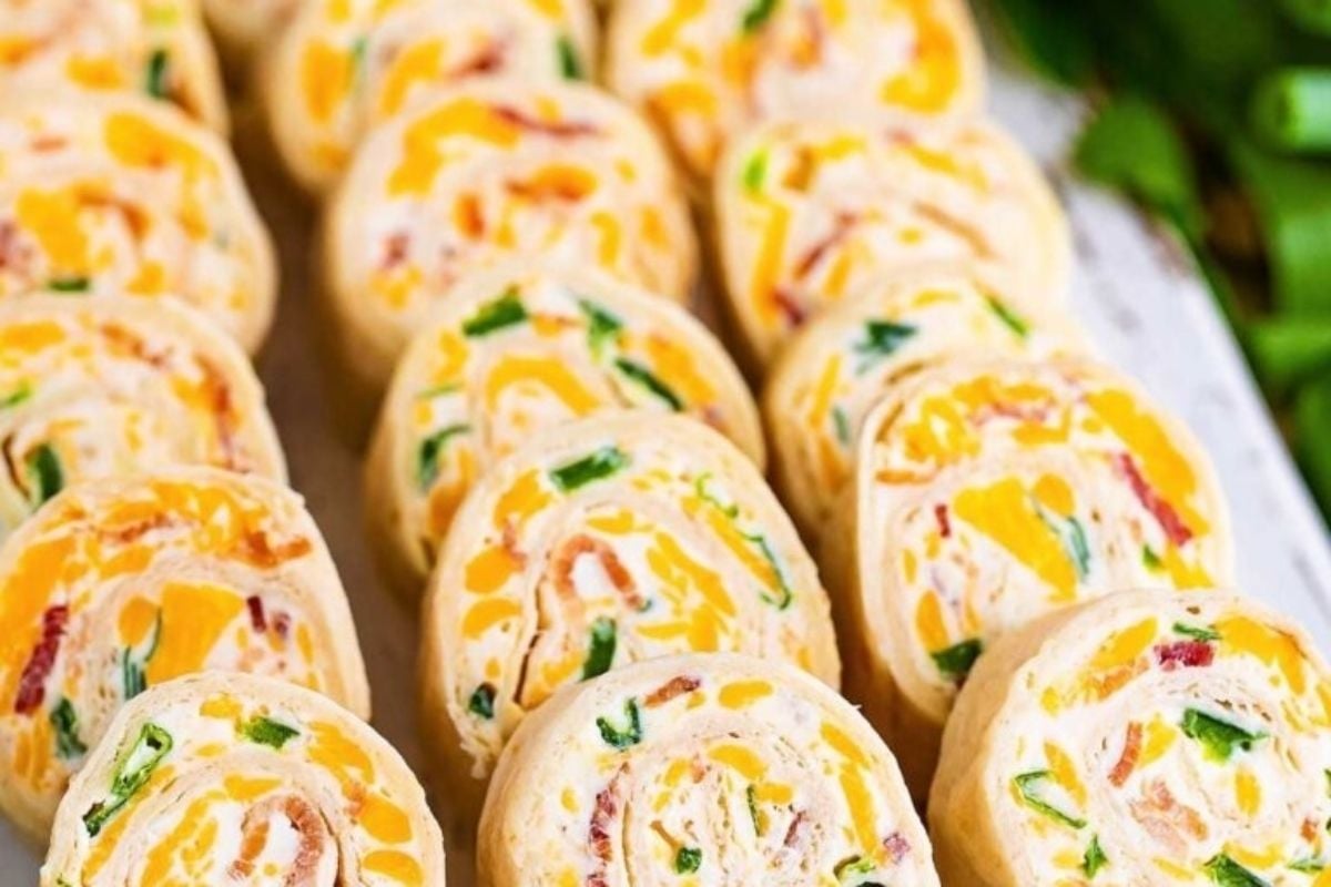 A tray of cheese and bacon rolls, perfect for potluck sides, on a white plate.