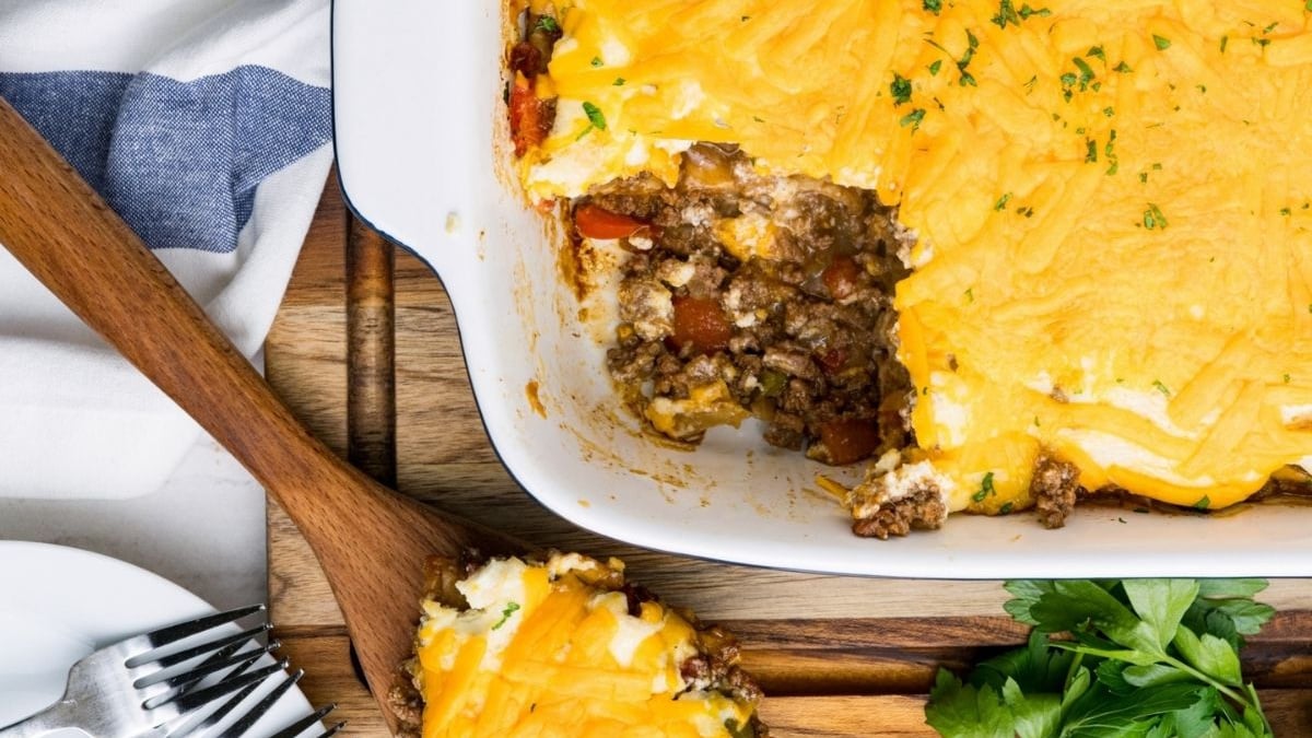 A freshly baked shepherd's pie with a scoop removed, revealing its biscuit-layered filling.