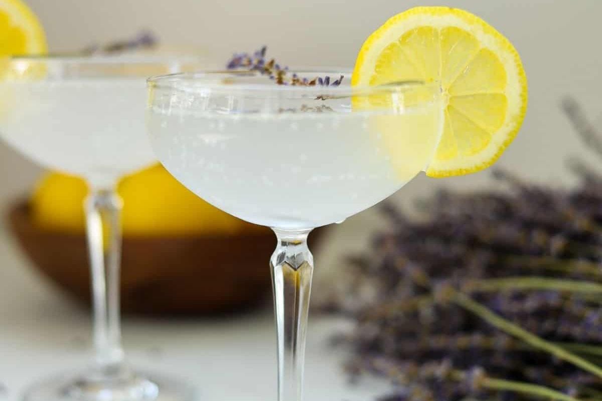 Two Easter cocktails garnished with lemon and lavender sprigs on a table.