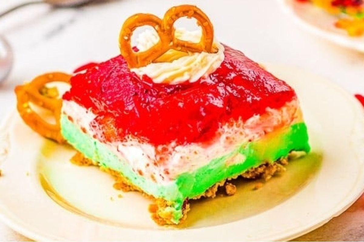 A piece of cheesecake with jello salads and pretzels on top.