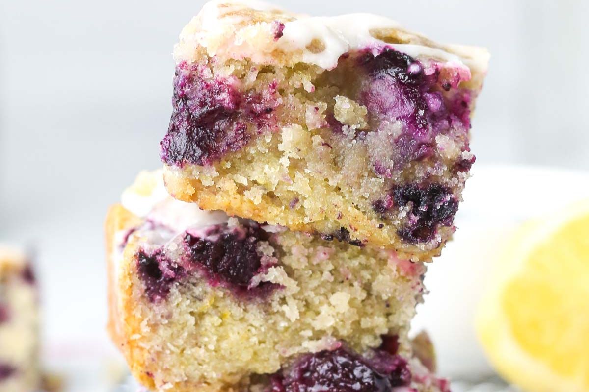 An Easter lemon blueberry cake square with a dripping glaze on top.