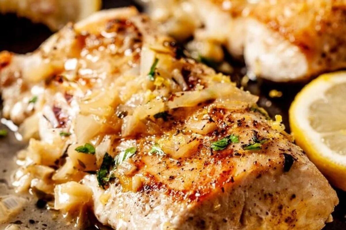 Grilled chicken breasts topped with herbs and garnished with lemon slices, perfect for Easter dinner.