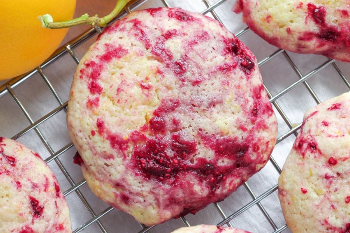 Freshly baked raspberry muffins on a cooling rack with Easter cookies in the background.