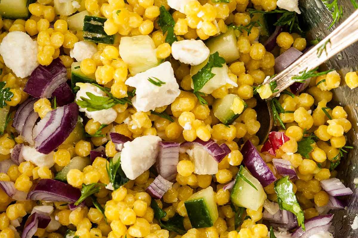 A close-up of a fresh couscous salad with cucumber, red onion, parsley, and herbs, perfect for Easter sides.