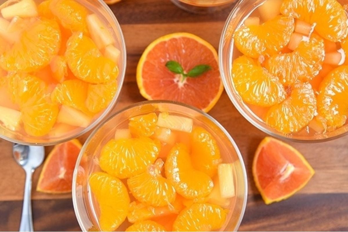 A bowl of orange jello salads with slices of oranges.