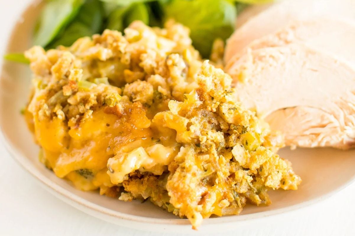 A plate of Easter dinner food showing a serving of broccoli casserole alongside slices of roasted turkey.